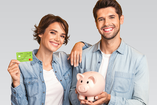 Couple holding debit card and piggy bank