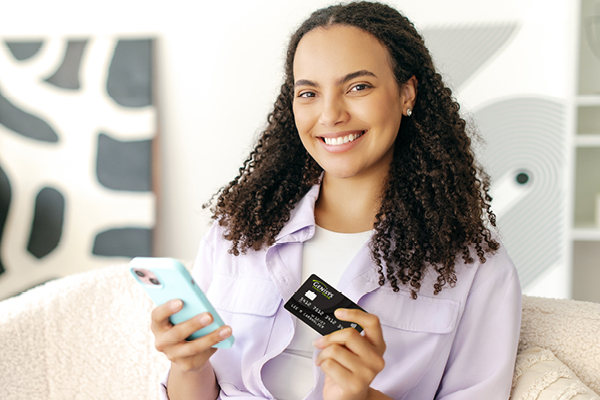 Woman holding credit card in hand looking at camera