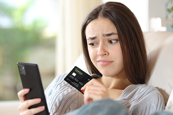 Young woman holding credit card and cell phone in hand
