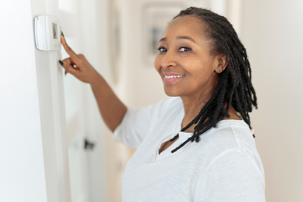 Woman smiling and pointing at thermostat