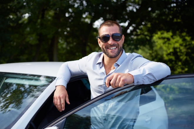 Man smiling outside of car while holding keys