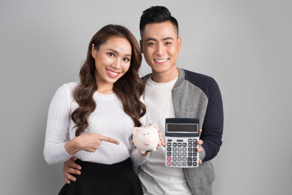 Young Asian Couple holding piggy bank and calculator
