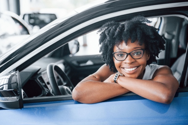 Woman smiling in her car, wearing glasses