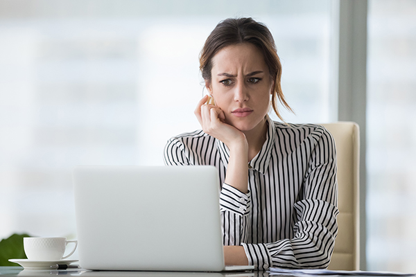 Woman with puzzled look, staring at computer