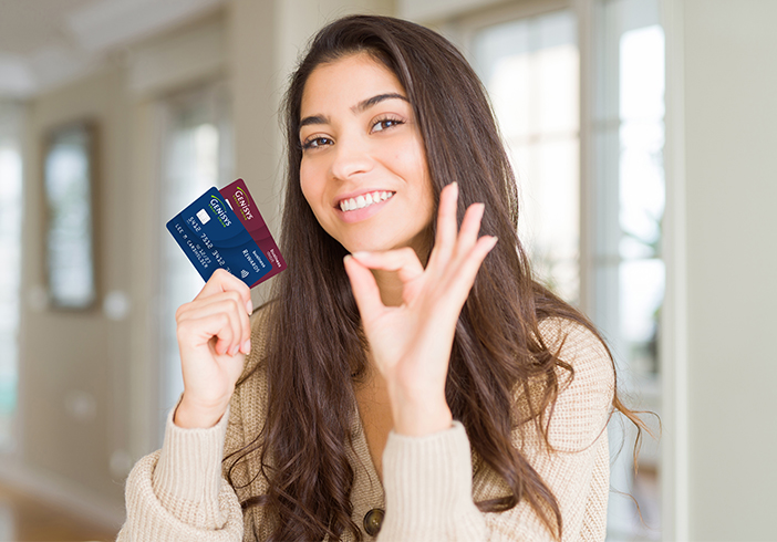 Woman holding up Genisys Business Credit and Debit cards