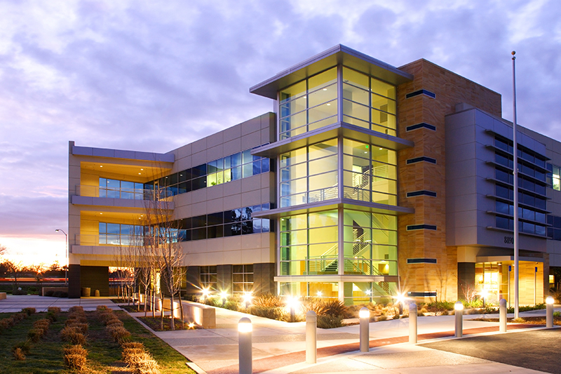 view of a commercial office building with windows lit up at dusk