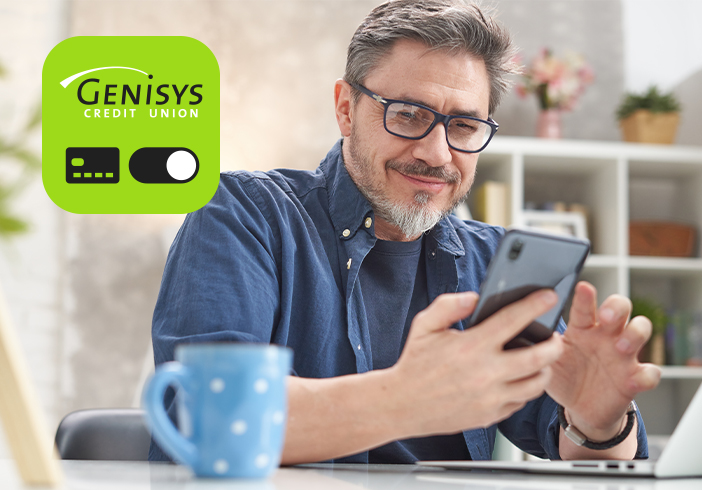 man on phone at the table with Genisys Card Controls app icon