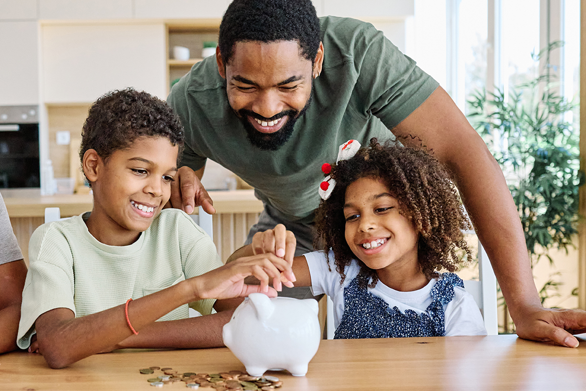 Father helping son and daughter save money with piggy bank