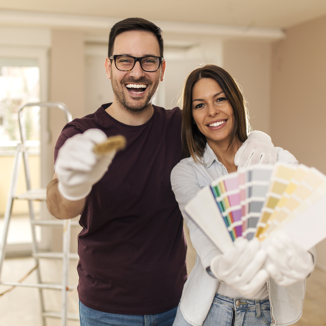happy couple with paint brushes and paint swatches