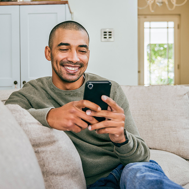 man sitting on couch looking at smartphone
